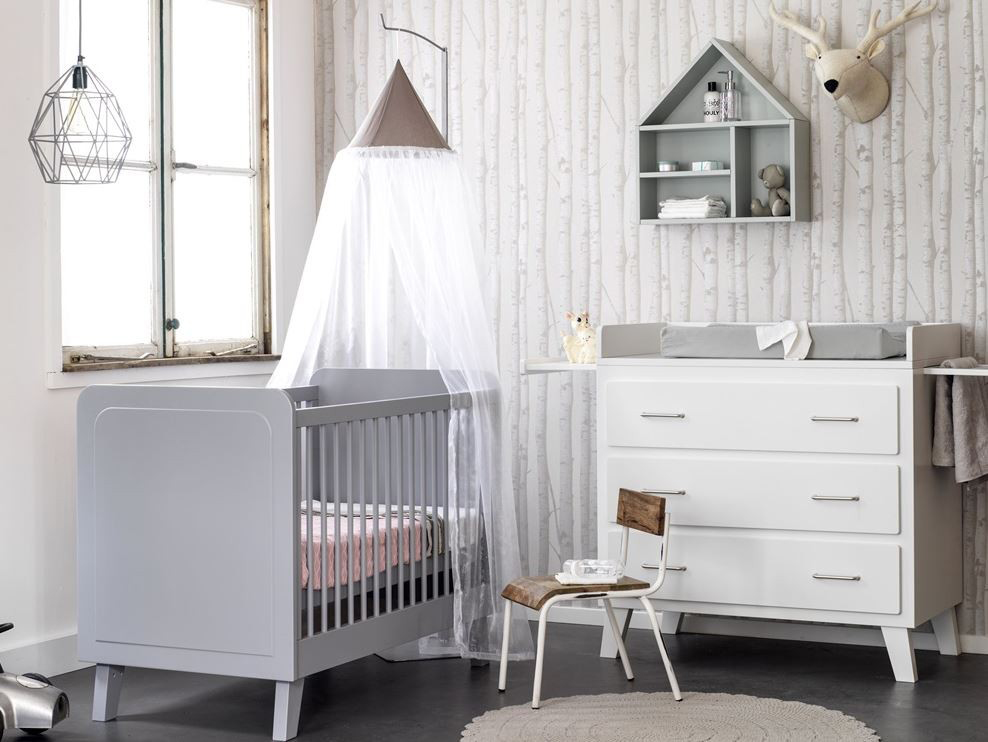 Trendy kinderkamer met een witte commode en grijs ledikant.