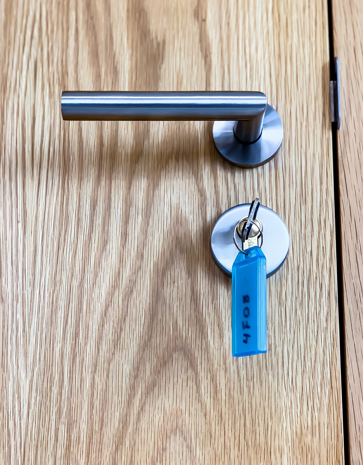 Moderne houten deur met sleutel en een opvallende sleutelhanger.