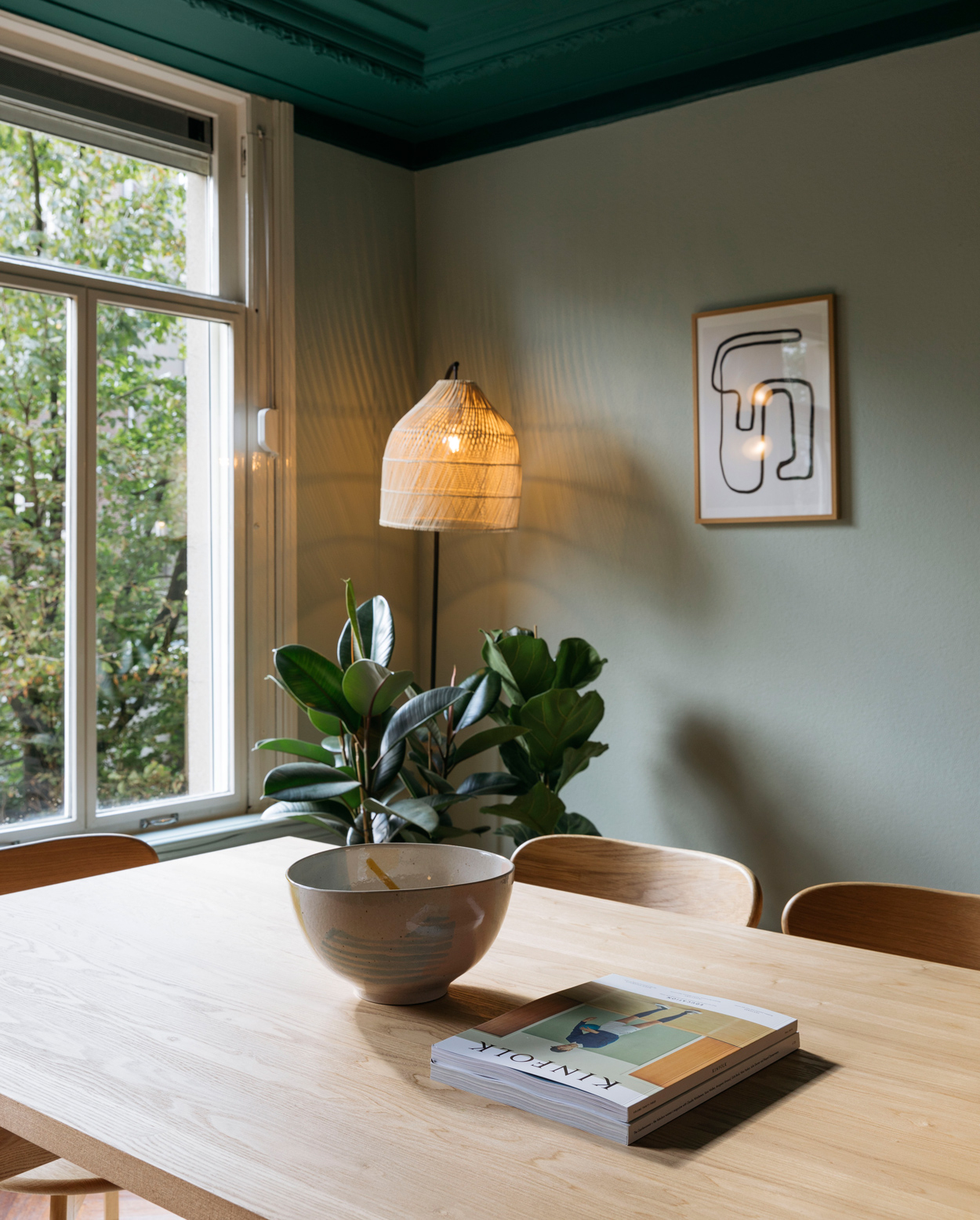 Een natuurlijke sfeer met een grote houten eettafel en grote kamerplant. 