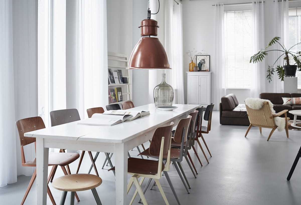 Trendy, industrieel interieur met vintage eetkamerstoelen.