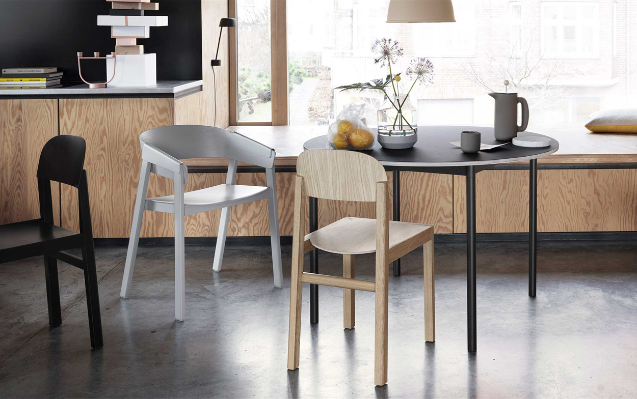 Ronde tafel met Scandinavische designstoelen van het merk Muuto. De witte elegante Cover Armchair heeft een gebogen rugleuning en gevouwen armleuninghoezen.