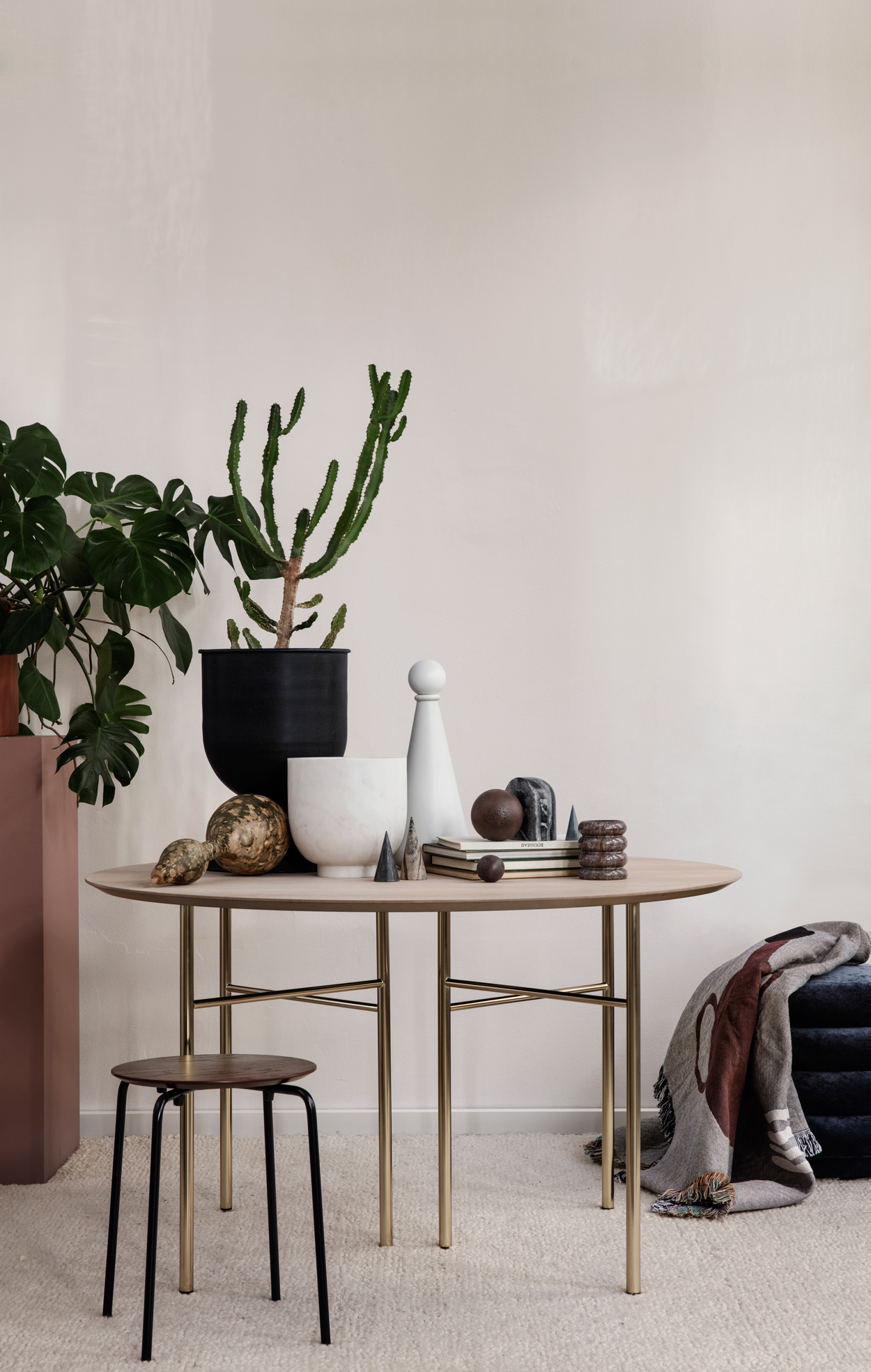 Ferm Living ronde tafel met krukje met rond-, koker en bolvormige woonaccessoires.