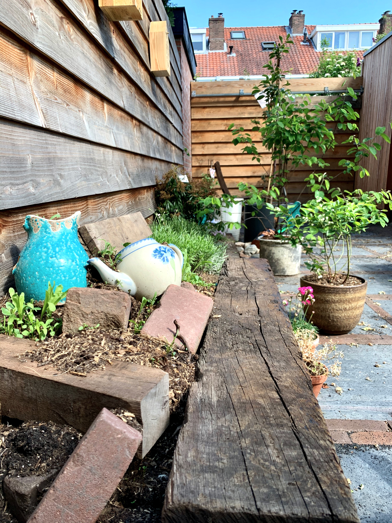 Tip voor een mooi wild hoekje met bloemen: verzamel oude stenen, pallets en potten en bedek deze met aarde en wilde bloemenzaden.