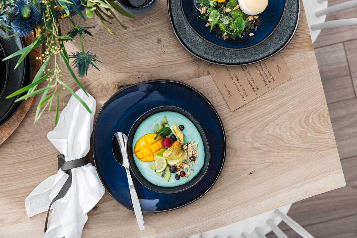 Een donkerblauw bord is prachtig in een natuurlijke setting met veel hout en groen.