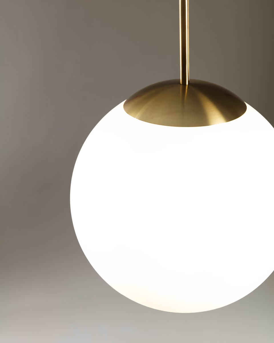 De matglazen bol van deze ronde hanglamp heeft messing accenten. Net als de zon, brengt de moderne lamp een warme gloed in de kamer.