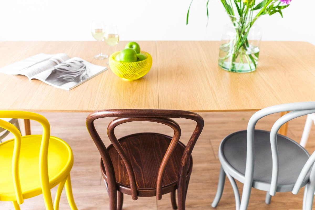 Klassiek caféstoelen met gebogen hout in trendy kleuren aan een moderne eettafel.