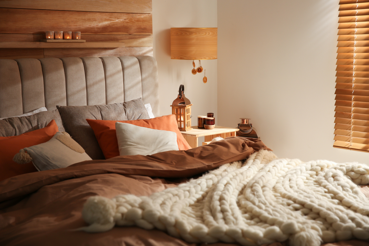 Kleuren zoals oranje en een gebreide sprei geven warmte aan je slaapkamer. 